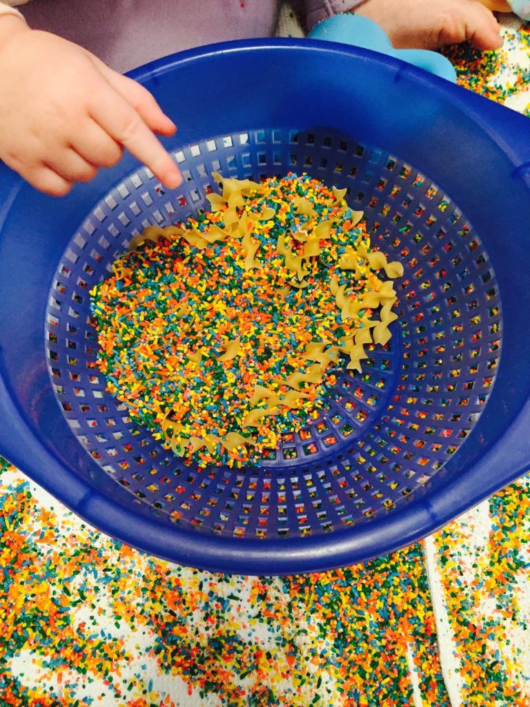 Sifting pasta from rice, 12 Colored rice activities, 12 colored rice play ideas, sensory activity, activities for one year old, montessori activities for a toddler, development promoting activities for toddlers, activities for 13 month old, activities for 14 month old, activities for 15 month old, activities for 16 month old, activities for 17 month old, activities for 18 month old, activities for a toddler, activities for one year olds, activities for two year olds activities, rice play